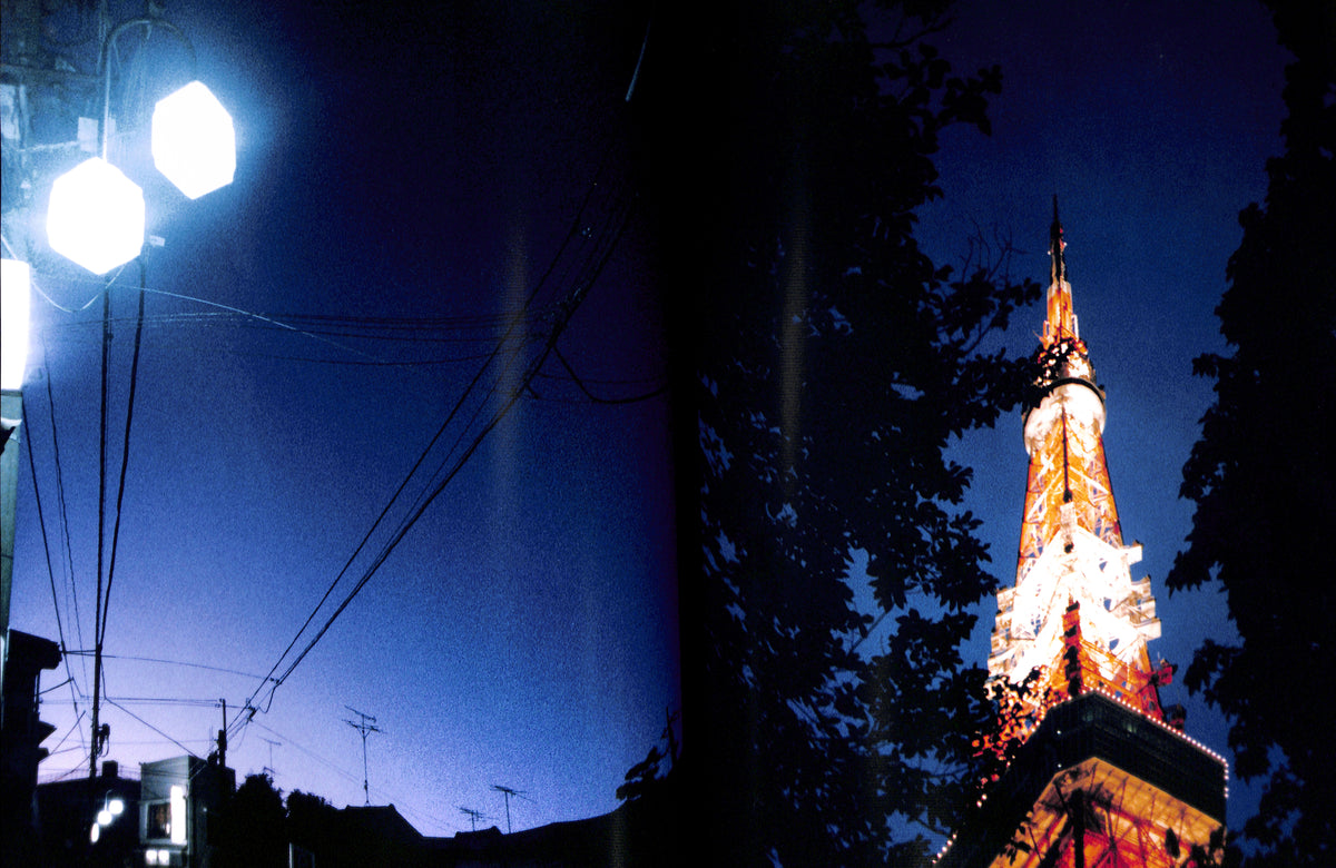 Interior spread of HIROMIX / Hikari with Tall illuminated tower with streetlights and power lines against a dark blue sky.