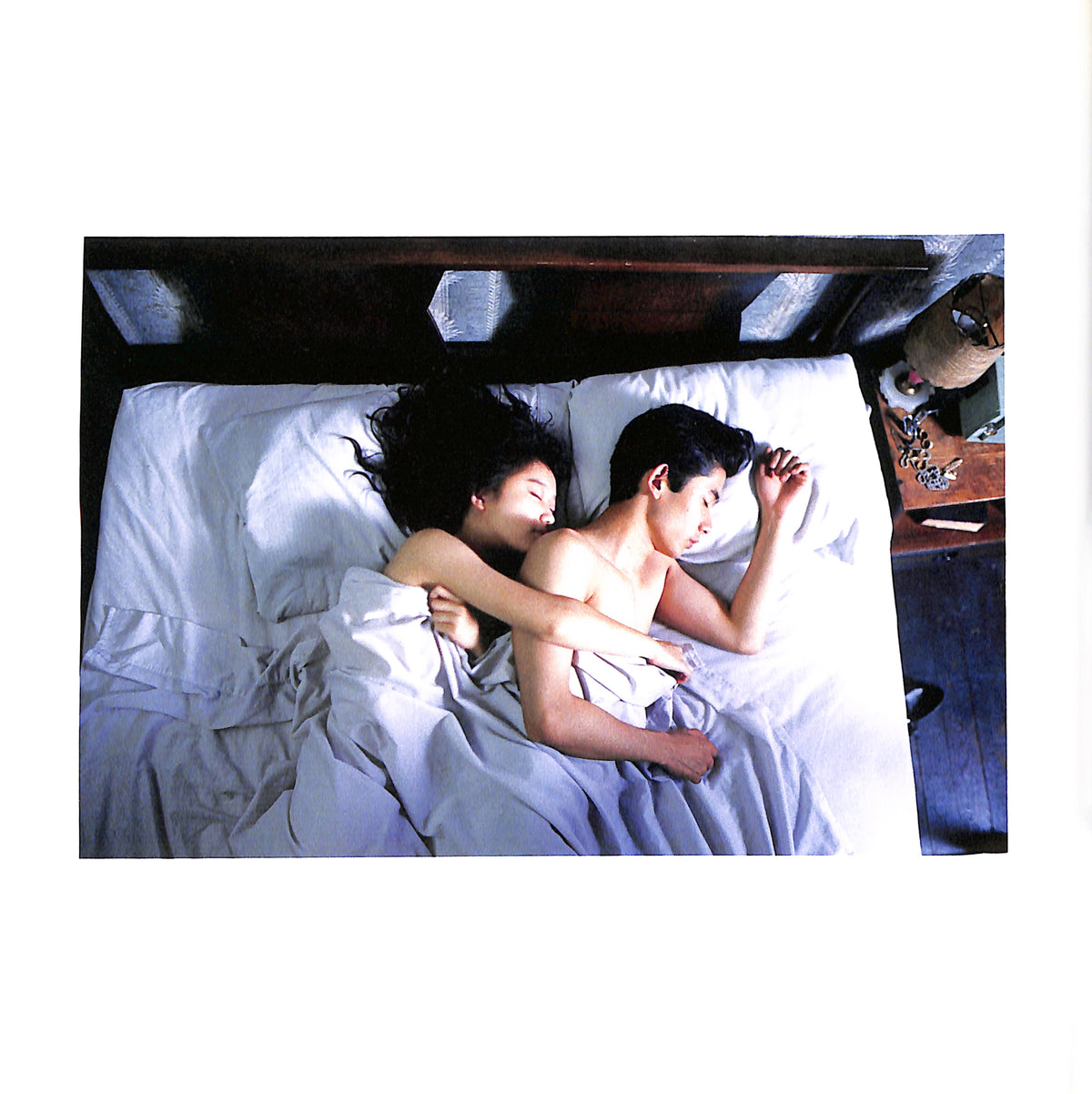 Internal page - JIM JARMUSCH & MASAYOSHI SUKITA / MYSTERY TRAIN. Two people lying in bed together, partially covered by white sheets.