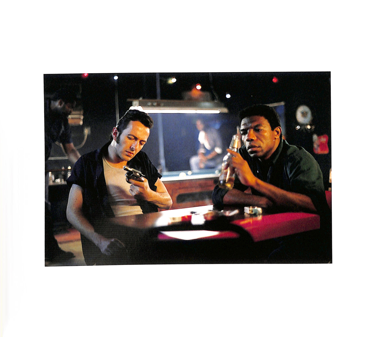 Internal page - JIM JARMUSCH & MASAYOSHI SUKITA / MYSTERY TRAIN. Two men sitting at a bar, one holding a gun and the other a bottle.