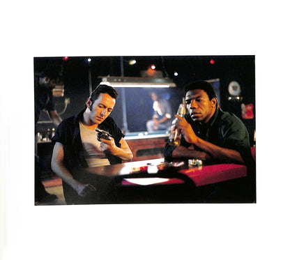 Internal page - JIM JARMUSCH & MASAYOSHI SUKITA / MYSTERY TRAIN. Two men sitting at a bar, one holding a gun and the other a bottle.
