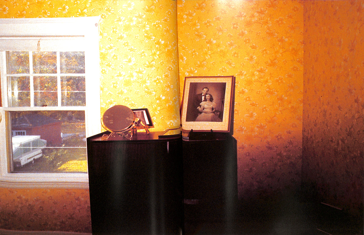 Room interior with yellow walls, a window, and a framed photo on a table.