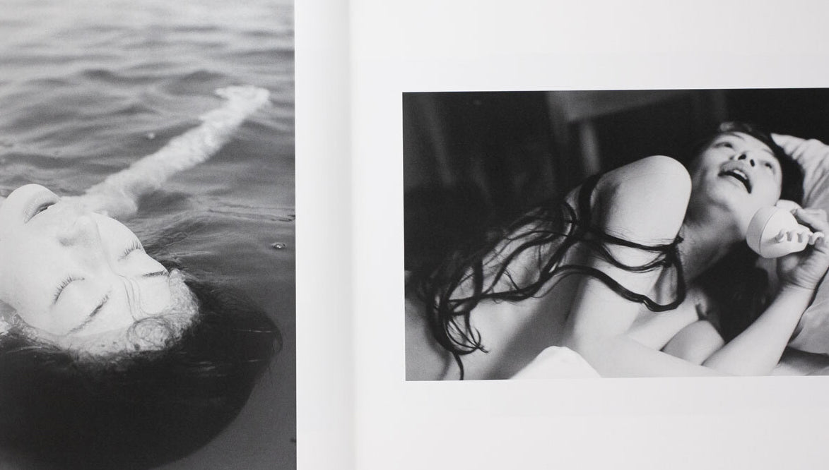 MASHISHA FUKASE / Yoko internal - Black and white photo of a person lying on water with another person holding their feet.